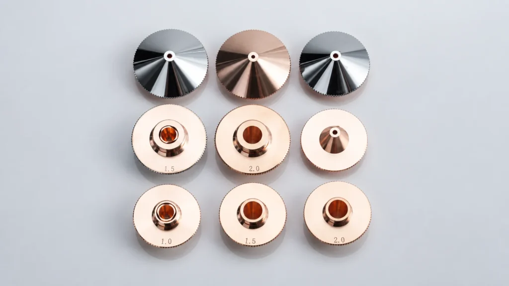 Nine copper and silver laser-cutting nozzle samples on a continuous light-gray background