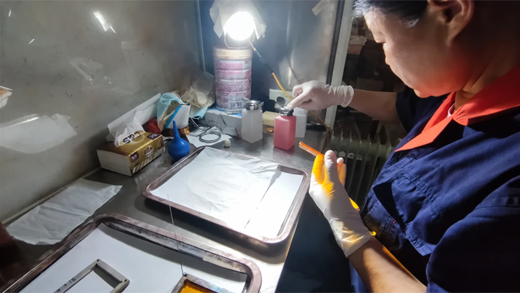 Optical component being inspected by hand under a work light