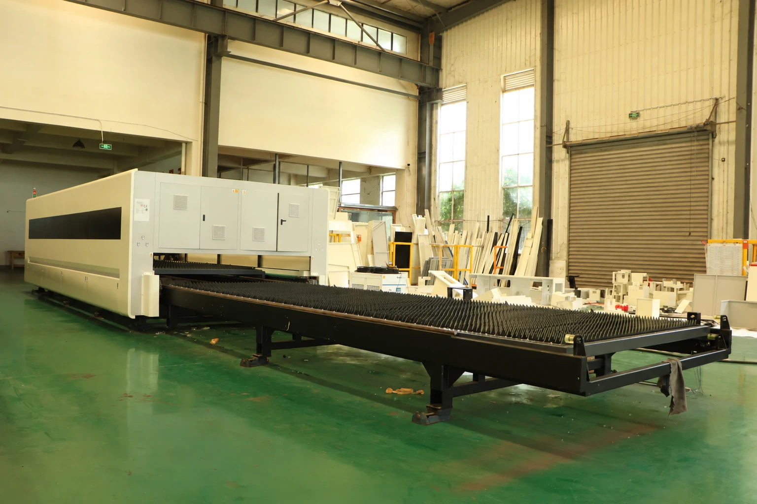 Enclosed sheet cutting machine with an extended exchange table in a manufacturing workshop